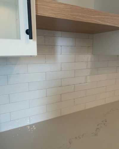 Kitchen wall with light white subway tiles and a dark cabinet corner above; a white and grey marble countertop.